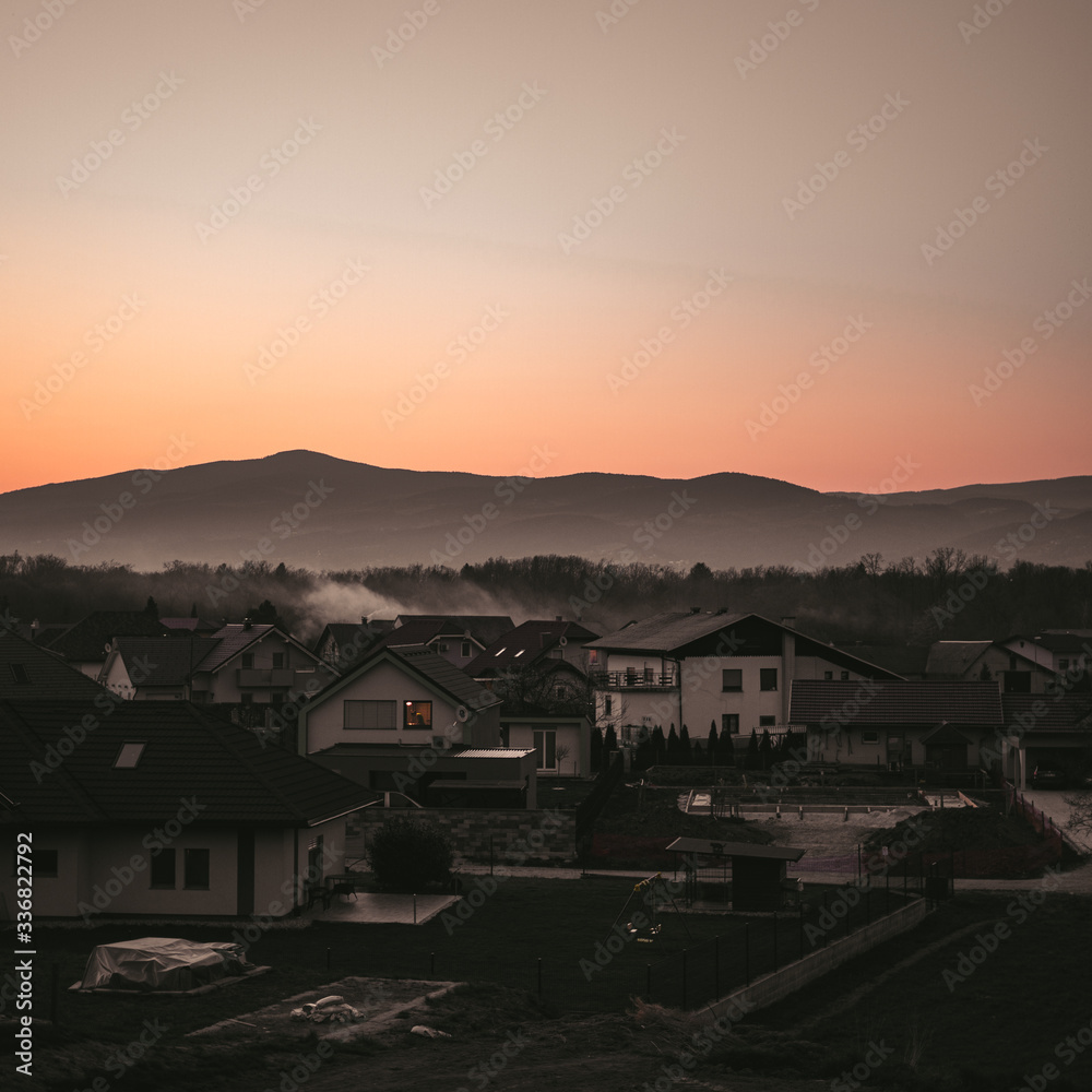 Moody shot of a town and beautifull mountains in sunset. - obrazy, fototapety, plakaty 