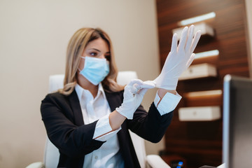 Young attractive caucasian businesswoman with mask and gloves in office. COVID - 19 virus protection