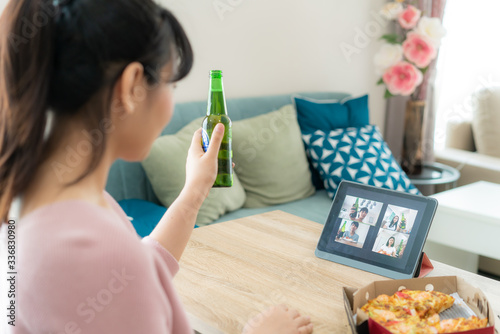 Asian woman virtual happy hour meeting party and drinking alcohol beer online together with her friend in video conference with digital tablet for a online meeting in video call for social distancing.