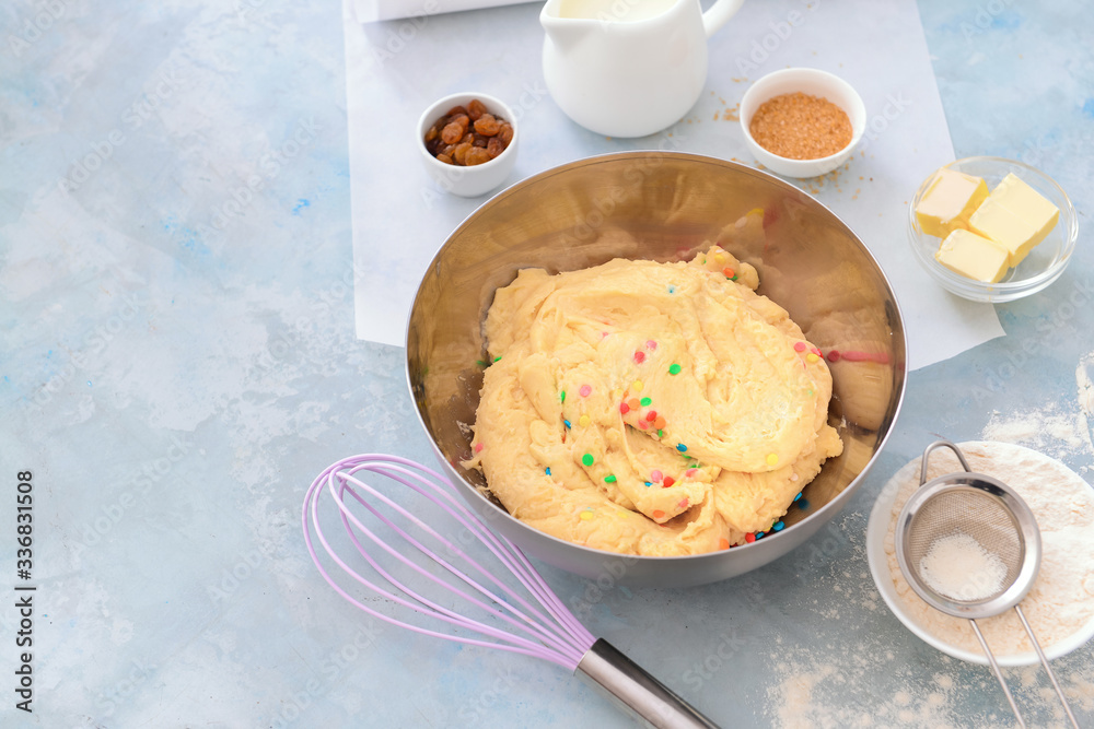 Bowl with sweet dough and products on color background
