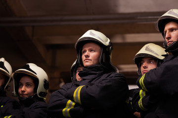 Wall Mural - Group of six professional firefighters standing together. Firefighters wearing uniforms and protective helmets.