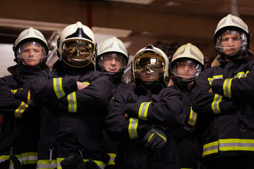 Wall Mural - Group of six professional firefighters standing together. Firefighters wearing uniforms and protective helmets.