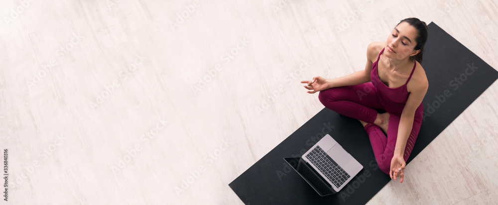 Stay home. Millennial girl in lotus yoga pose listening to online meditation on laptop, panorama. Top view - obrazy, fototapety, plakaty 