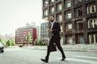 © Maskot - Confident businessman with bag crossing road