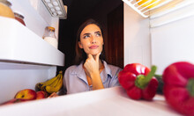 Thoughtful Housewife Looking Into Fridge, View From Inside