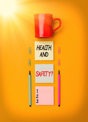 Poster - Handwriting text writing Health And Safety. Conceptual photo procedures intended to prevent accident in workplace Coffee cup blank colored sticky note two ballpoints clips yolk background