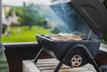 Smoke Coming Out Of A Smokestack Of A Small Black Smoker Grill Or Barbecue, Loaded With Chicken Meat And Vegetables.