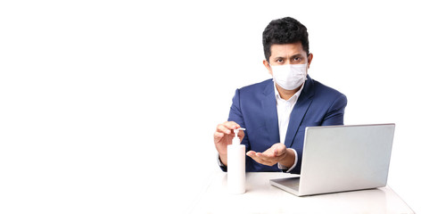 Business man using alcohol gel and wearing medical mask. has The computer page in front of. on white background in studio With copy space. Concept work from home covid-19.