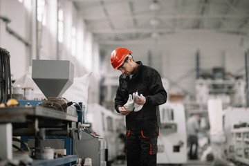 Portrait of worker in factory. Young handsome man working in factory. 