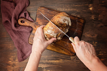 Wall Mural - Woman hands cut fresh organic artisan bread. Healthy eating, buy local, homemade bread recipes concept. Top view, flat lay