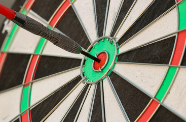 Close up Dart arrow hitting on dartboard on wooden Success hitting target aim goal achievement concept background – three dart in bull’s eye.