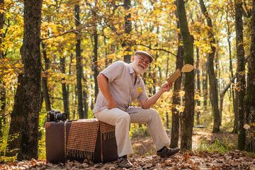 Hobby and leisure. Grandfather with vintage suitcase in nature. United with nature. Weekend in nature. Vacation and relax. Retirement concept. Elderly people. Mature man with white beard in forest