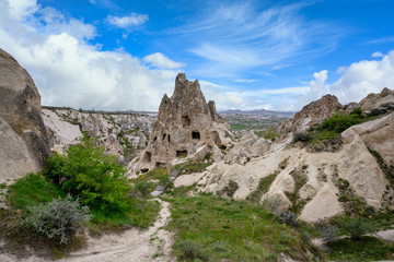 Sticker - The Zelve Open Air Museum in Cappadocia, Turkey, has many sharp limestone mountains in the summer. There are green grass all over the area with blue skies.