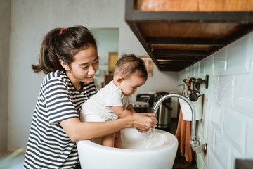 mother help her baby to wash hand in the sink