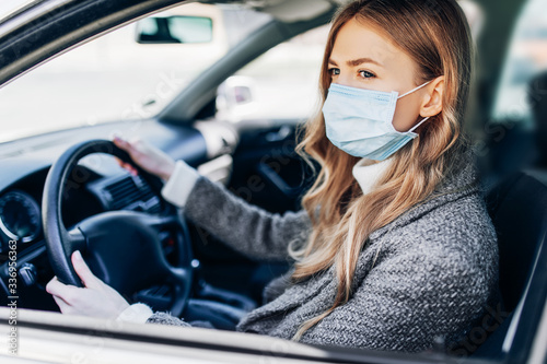 Fotomural Beautiful young girl in a mask sitting in a car, protective mask against coronav