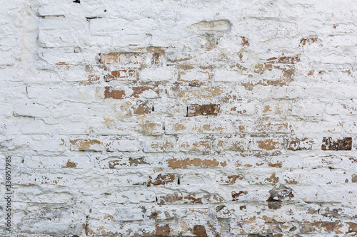 The brick wall is whitewashed, cracked old.