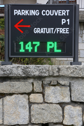 Cuadros en Lienzo Muret en pierre sur lequel est installé un panneau en métal indiquant que le parking couvert est gratuit et qu'il reste 147 places de stationnement
