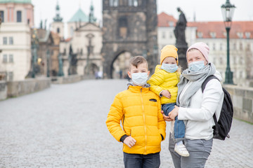 Woman with her children wearing  medical masks stand on empty Charles Bridge in Prague. Coronavirus epidemic concept