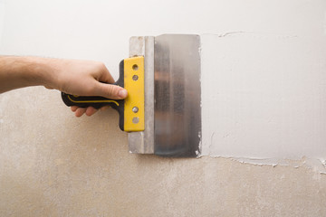 Worker hands using spatula and plastering old cement wall with putty. Closeup. Before and after.