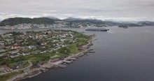 Forward Approaching Aerial Drone Footage Of A Luxurious Cruise Ship Leaving The Bay Of Alesund, The Most Beautiful Town Of Norway, While A Tugboat Performs A Water Salute By Spraying Water In The Air.