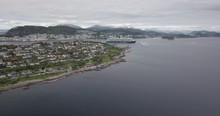Forward Approaching Drone Footage Of A Luxurious Cruise Ship Leaving The Bay Of Alesund, The Most Beautiful Town Of Norway, While A Tugboat Performs A Water Salute By Spraying Water In The Air.