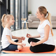 © FreepikCompany - Side view of mother and daughter doing a yoga pose at home