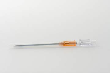 Orange intravenous cannula 14 G on white background, external diameter 2,1 mm, used in trauma, blood transfusion, surgery, ascites puncture.