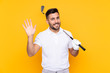 Golfer player man over isolated yellow background saluting with hand with happy expression