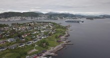 Approaching Drone Footage Of A Luxurious Cruise Ship That Is Leaving The Bay Of Alesund, The Most Beautiful Town Of Norway, While A Tugboat Performs A Water Salute By Spraying Water In The Air.