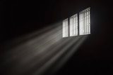 Fototapeta Big Ben - Beams of light through a barred prison cell window