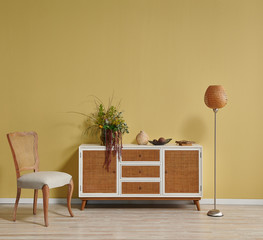 Yellow living room wall and wicker cabinet, orange lamp and frame style with chair.