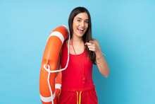 Lifeguard Woman Over Isolated Blue Background With Lifeguard Equipment And Surprised Expression While Pointing Front