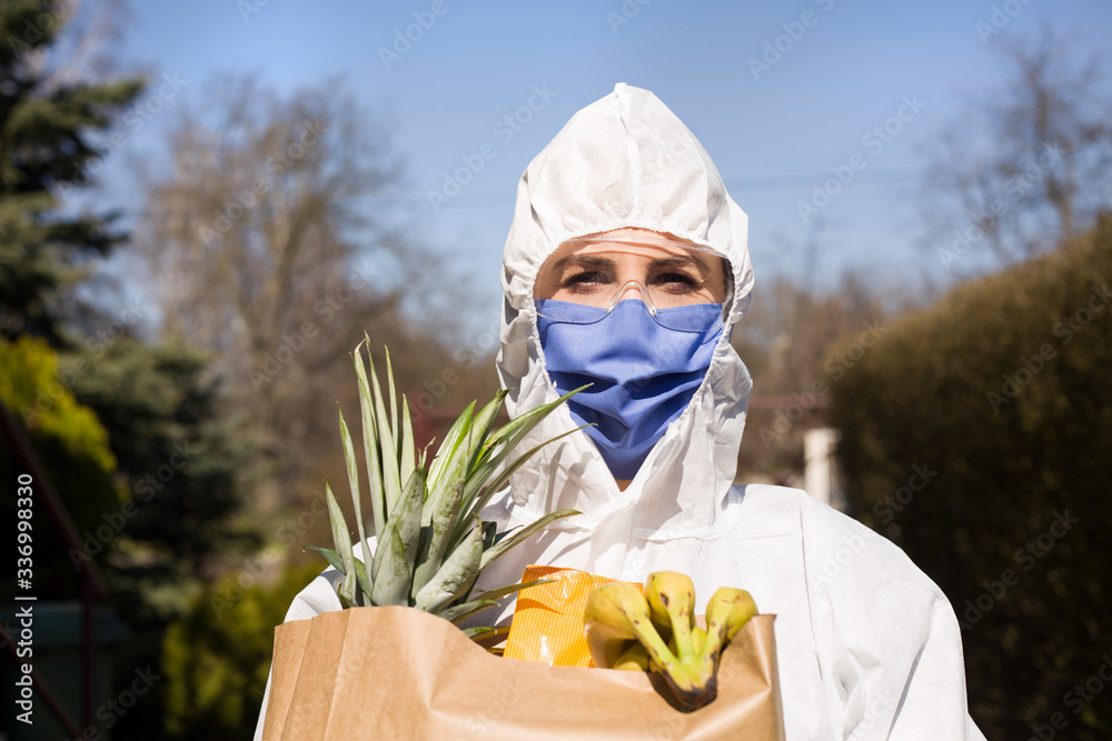 Kobieta w maseczce ochronnej niesie papierową torbę z owocami - obrazy, fototapety, plakaty 