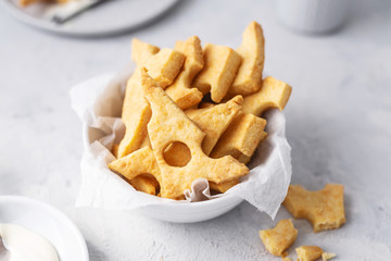 Wall Mural - Cheese crackers, salty snack concept. Cookies, piece of cheese on a gray background