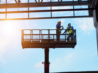 construction worker at construction site using lifting boom machinery