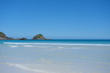 View of the horizon in the ocean. Sandy beach with white sand, clear blue ocean water with wave , horizon line with beautiful rocky islands