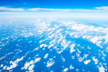 Beautiful clouds top view on a background of blue sky from the porthole of an airplane at altitude.