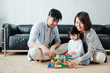 Mom and Dad and daughter at home building blocks