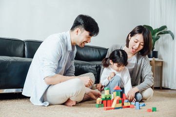 Mom and Dad and daughter at home building blocks