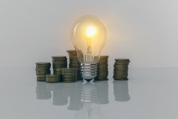 Hand holding a light bulb with coins stack. Creative ideas for saving money concept. Money management for the future.