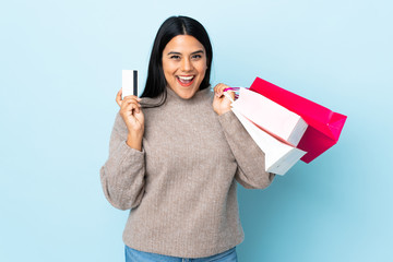 Wall Mural - Young latin woman woman isolated on blue background holding shopping bags and a credit card