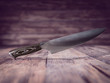 A knife suspended in the air with heavily blurred bokeh. Boards background.