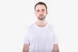 © Xristoforov - Unshaven man in casual t-shirt looks sad at camera. Isolated, white backgroung