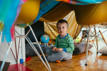 Little Boy Playing In His Built Indoor Fort In Living Room