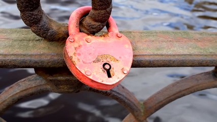 Poster - red lock as heart fastened to the fence embankment.