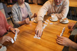 © AnnaStills - Close-up of group of people sitting at wooden table and playing in domino together