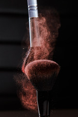 Wall Mural - Powder in motion and makeup brushes close-up on a dark background