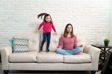 Wall Mural - Mother trying to meditate with restless kid