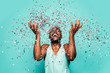 © MyMicrostock/Stocksy - Cheerful black ethnic man throwing confetti on air.