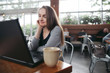 © Rob and Julia Campbell/Stocksy - Mature woman chatting on laptop at coffee shop.
